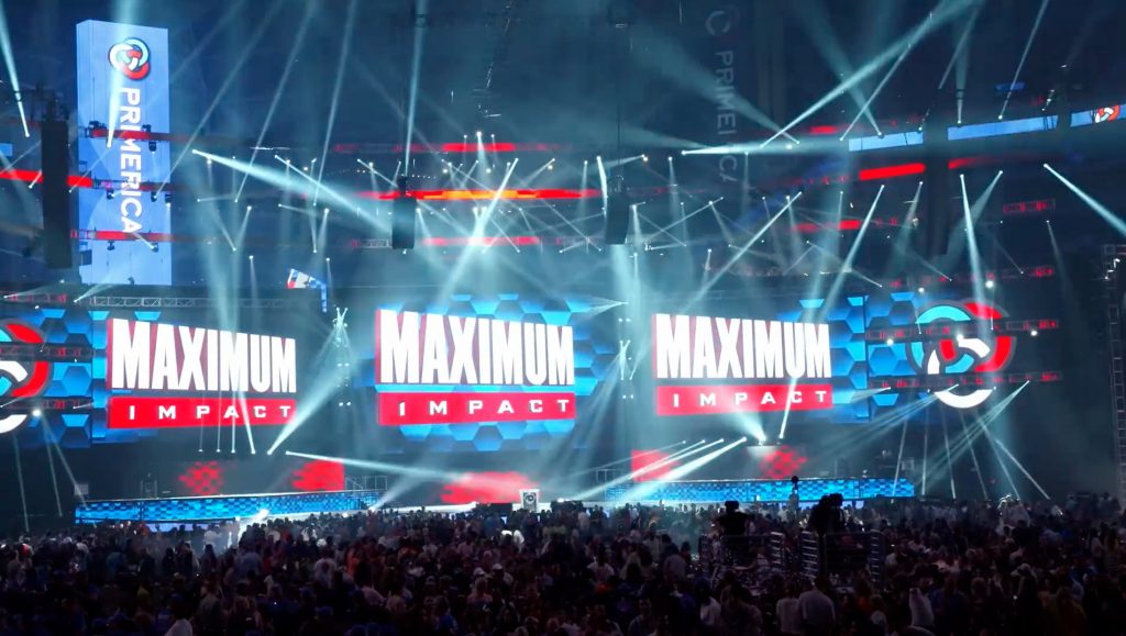 A light show over a stage and crowd at the Primerica International Convention with a large crowd and multiple screens reading “Primerica” and “Maximum Impact.”