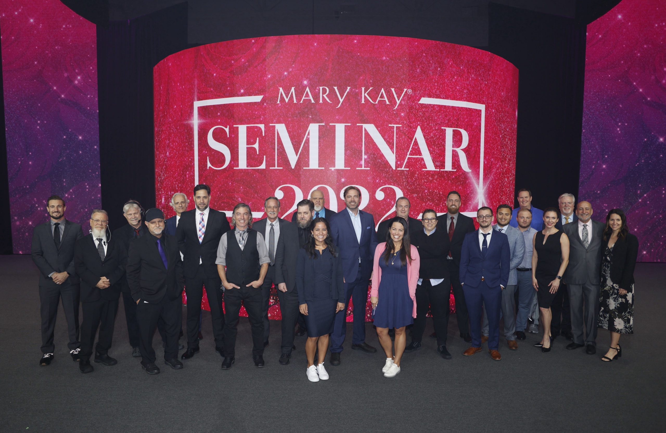 MIG and Mary Kay team posing in front of screen with Seminar on show screen