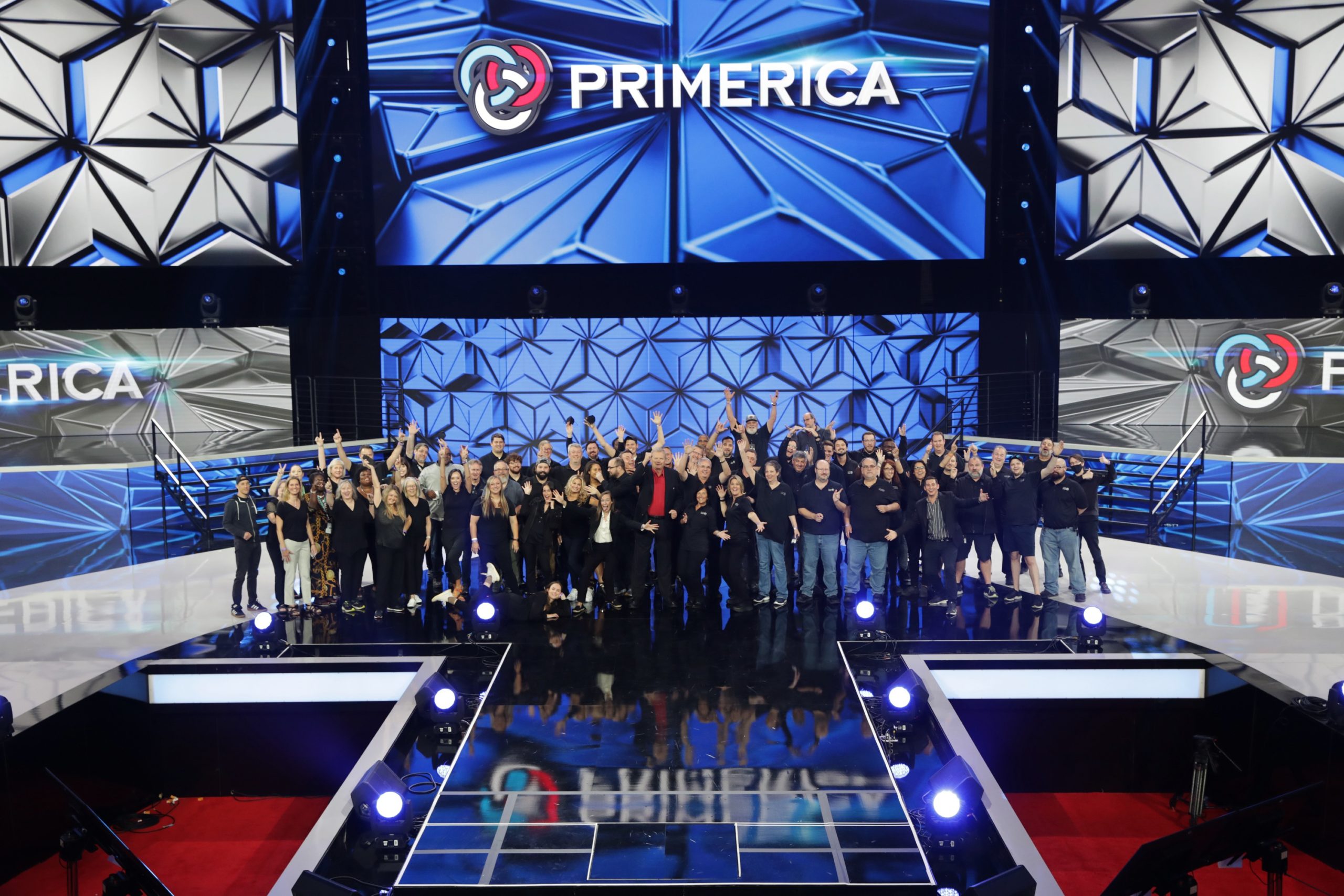 A light show over a stage and crowd at the Primerica International Convention with a large crowd and multiple screens reading “Primerica” and “Maximum Impact.”